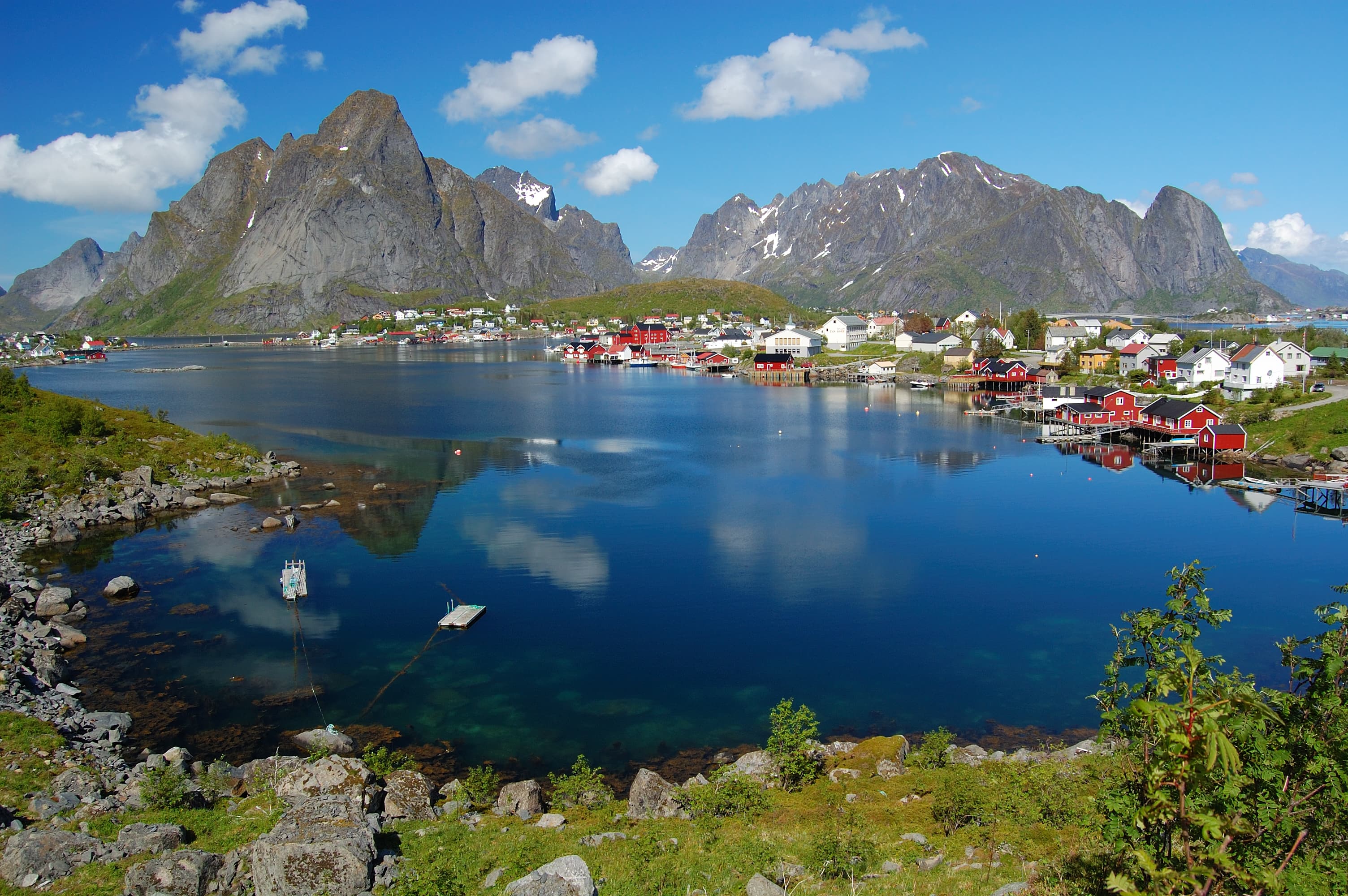 Reine auf den Lofoten mit Fischerhütten und Bergen, die sich im Wasser spiegeln