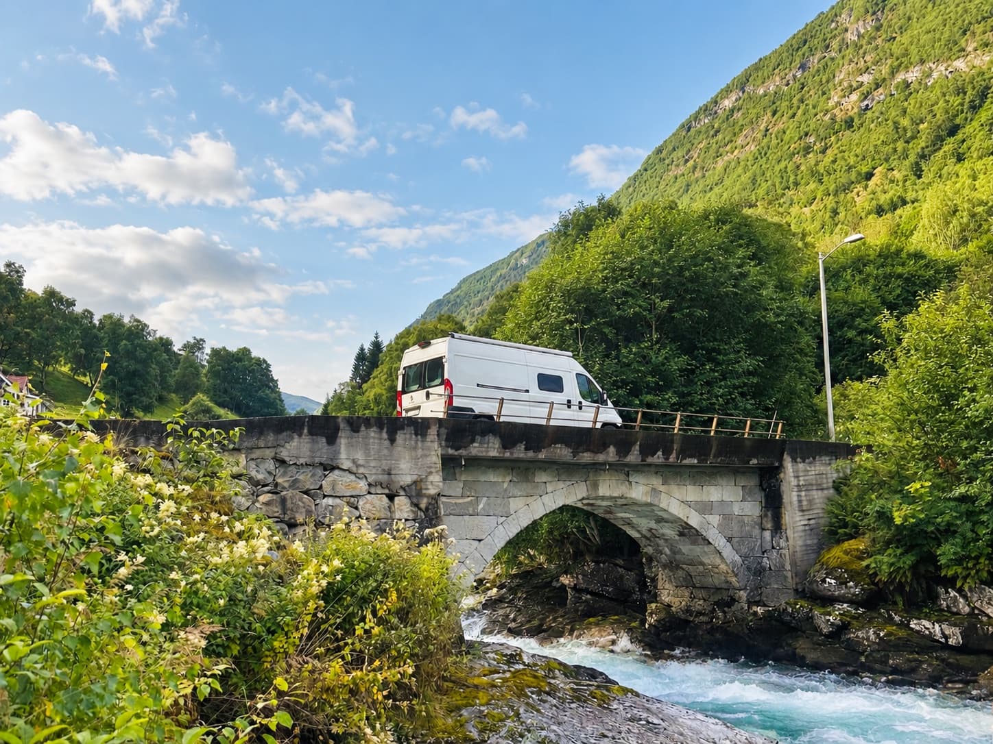 Campervan crossing a stone bridge over a mountain river